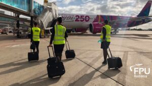 Wizz Air crew members walking towards an aircraft on the airport apron.