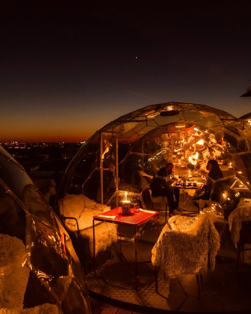 Dining inside a Linea rooftop igloo at sunset