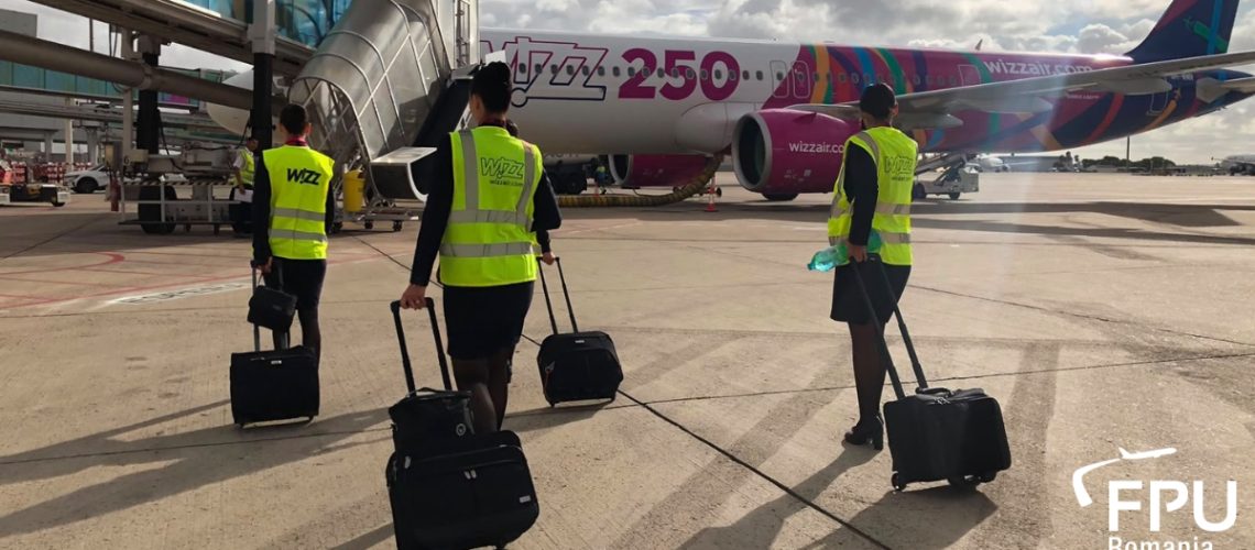 Wizz Air crew members walking towards an aircraft on the airport apron.